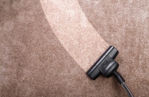 How often should carpets be cleaned? - vacuum being pulled over a brown carpet