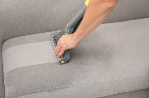 Upholstery stain removal - contractor vacuuming couch upholstery